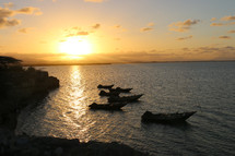 boats along a rocky shore in Haiti at sunset 