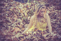 A woman lying in fall leaves. 