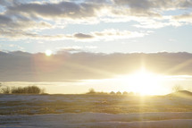 sunrise over a snow covered field on a farm 