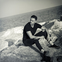 young man sitting on the rocks near the sea.