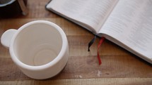 empty coffee cup and pages of a Bible 
