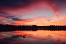 A beautiful landscape of a stunning sunset that reflects on the calm waters below.