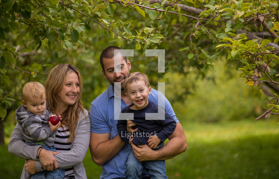 a family standing in an apple orchard 