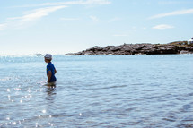 a little boy walking into the ocean water 