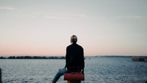 a young woman sitting in a harbor at sunset 