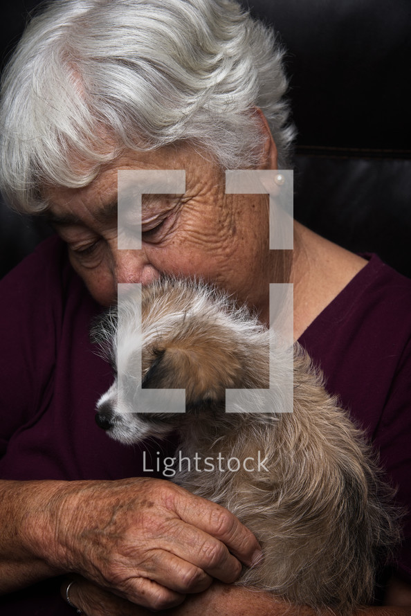 elderly woman snuggling a puppy 
