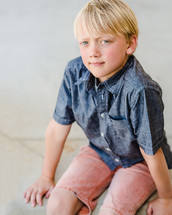 a boy child sitting on a curb 