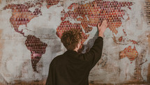 a man with his hands on a world map painted on burlap 