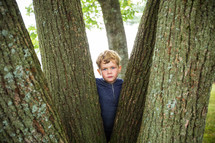 child hiding behind a tree