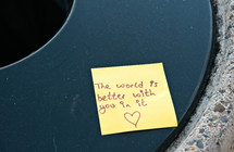 The world is better with you in it note  left on a trash can lid.