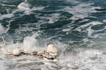 waves crashing onto salt covered rocks in the Dead Sea
