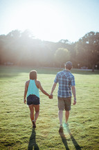 couple holding hands walking in a park 