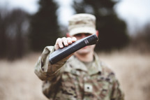 Christian soldier in a field praying holding a Bible 