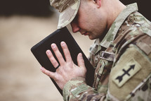 soldier holding a Bible praying 