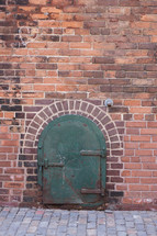 green metal door on a brick wall 