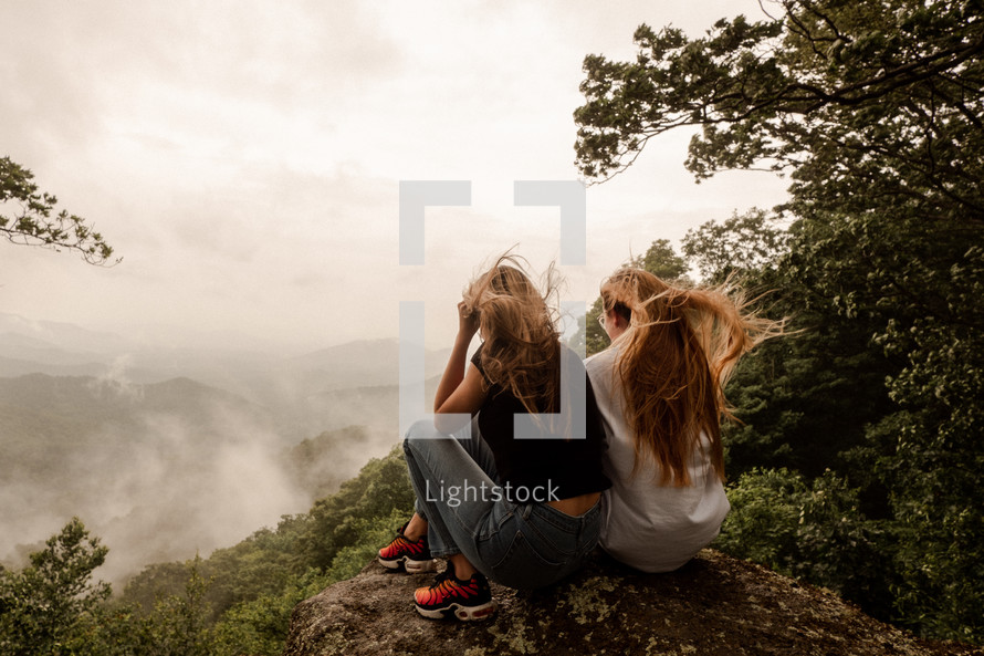 young women sitting on a mountaintop 