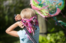 girl child hitting a piñata 