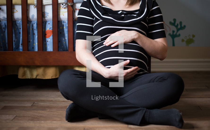 a mother sitting holding her pregnant belly