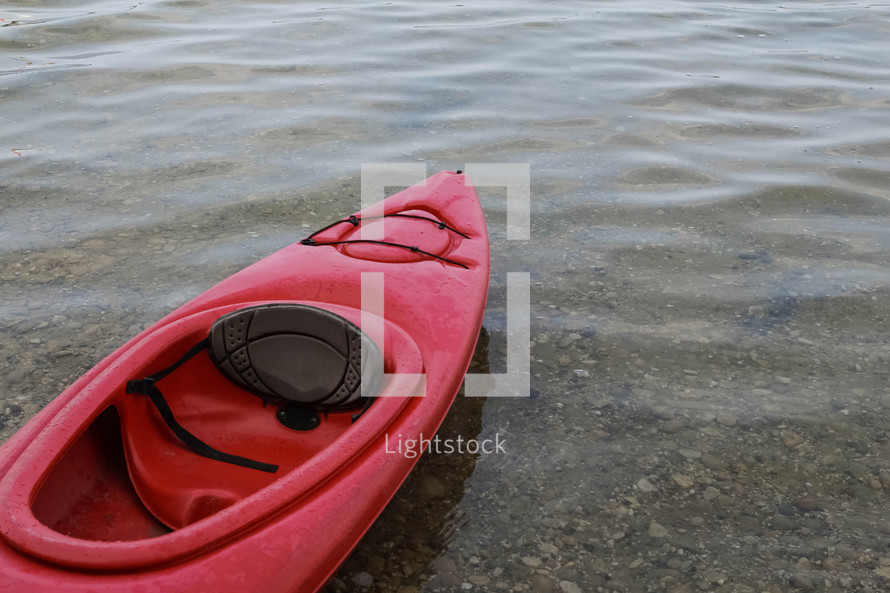 red kayak sitting on a lake shore