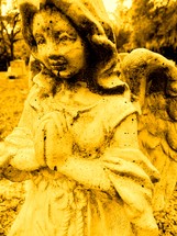 Yellow praying angel in a graveyard