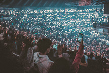 lights from phones in a stadium at a concert 