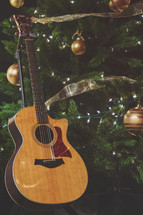 Christmas worship stock photo featuring an acoustic guitar and Christmas tree, ornaments and lights perfect for a social media story background or idea. 