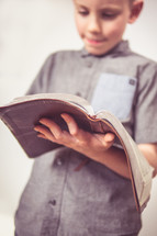 boy child standing reading a Bible 