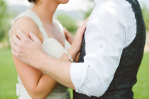 View of bride and groom holding each other; neck to waist