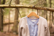 a shirt and sweater hanging on a branch 