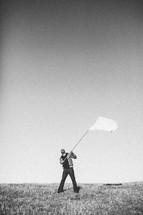 Man in field waving white flag.