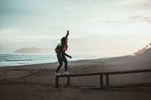  a woman balancing on a wood railing on a beach 