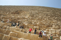people sitting on the sides of the pyramids in Egypt 