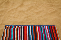 striped beach towel on sand background 