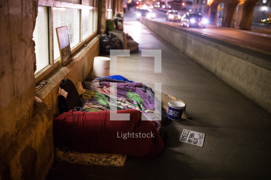 homeless sleeping bags on a city sidewalk 
