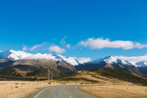 A highway leading to a snow covered mountain range.