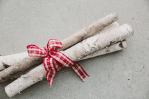 Birch logs tied together with red and white ribbon.
