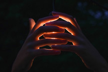 hands surrounding a light bulb