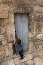 a boy at the entrance of an ancient door 