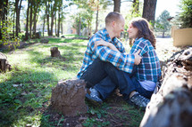 man and woman in plaid shirts snuggling in the woods 