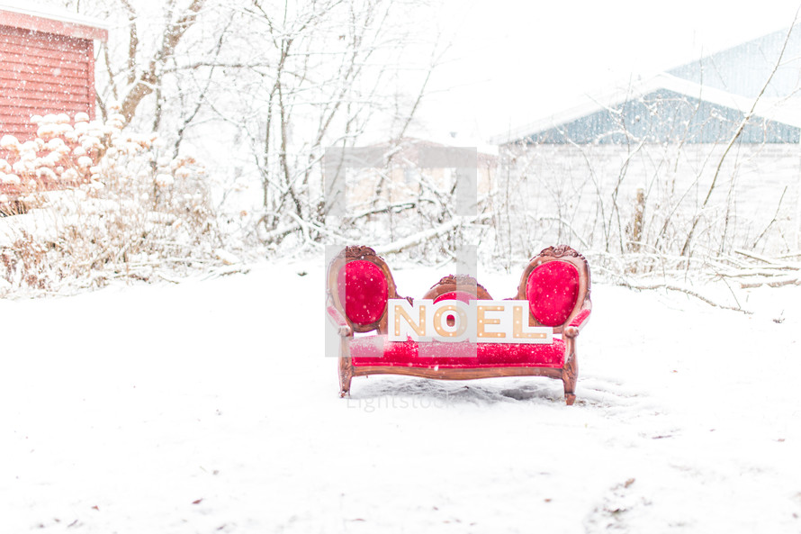a red chair in the snow with a sign of the word noel 