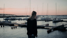 a young woman standing in a marina at dusk 