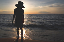 silhouette of a child standing on a beach at sunset 
