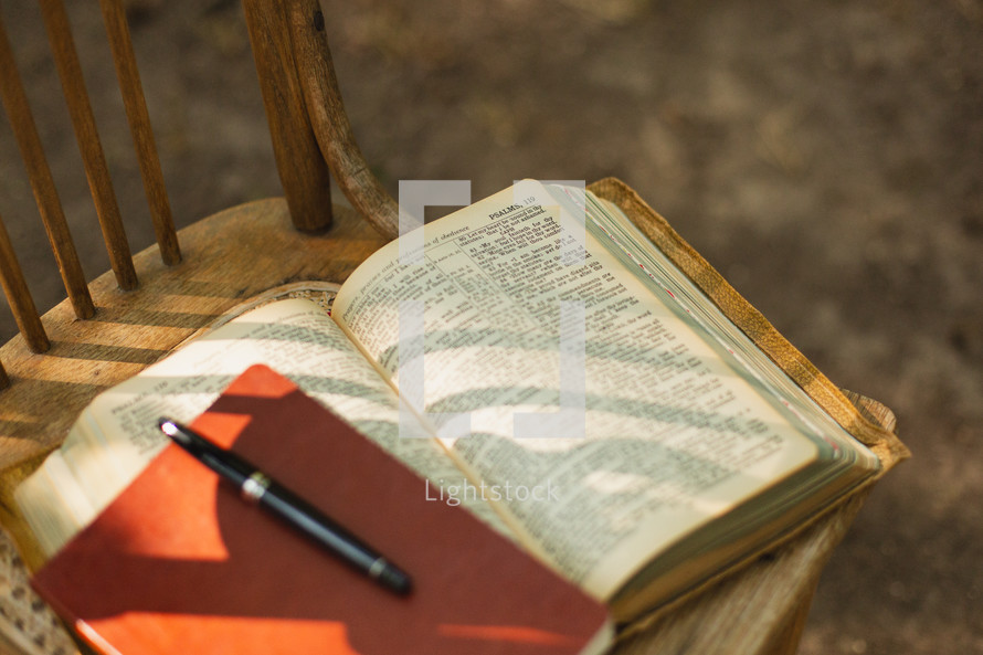 A Bible and journal on a chair.