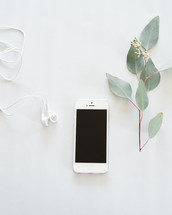 earbuds, cellphone, twig with leaves 
