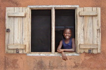 A little girl smiles from a window {Also try search for 'Ethnic Faces'} 