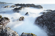 ocean water flowing over rocks 