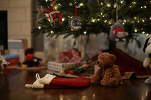 presents, stockings, and teddy bear under a Christmas tree 