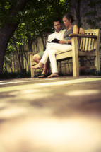 Couple reading Bible on park bench