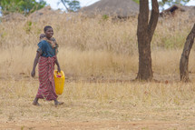 mother carrying a baby on her back carrying a jug of water