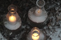 candles burning in glass lanterns dusted with snow